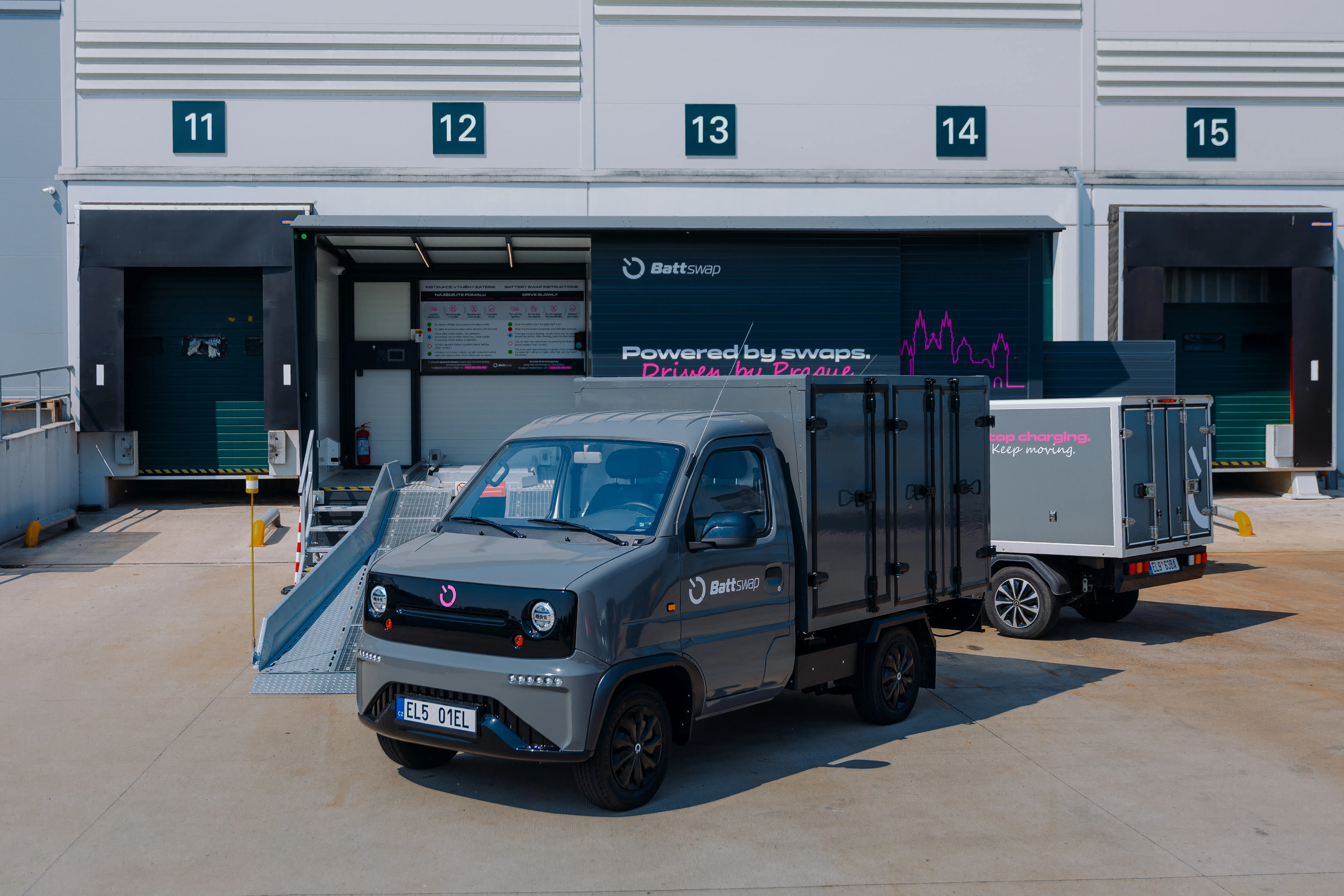 A Battswap electric truck and van parked in front of the swap station at a depot loading dock.