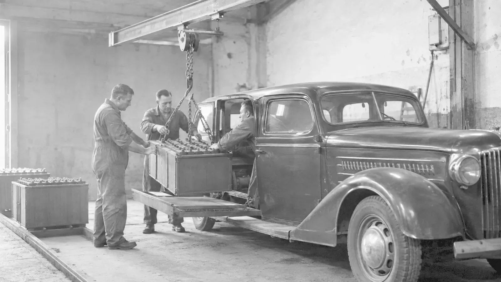 Battery being lifted out of a car in a garage on a chain hoist.