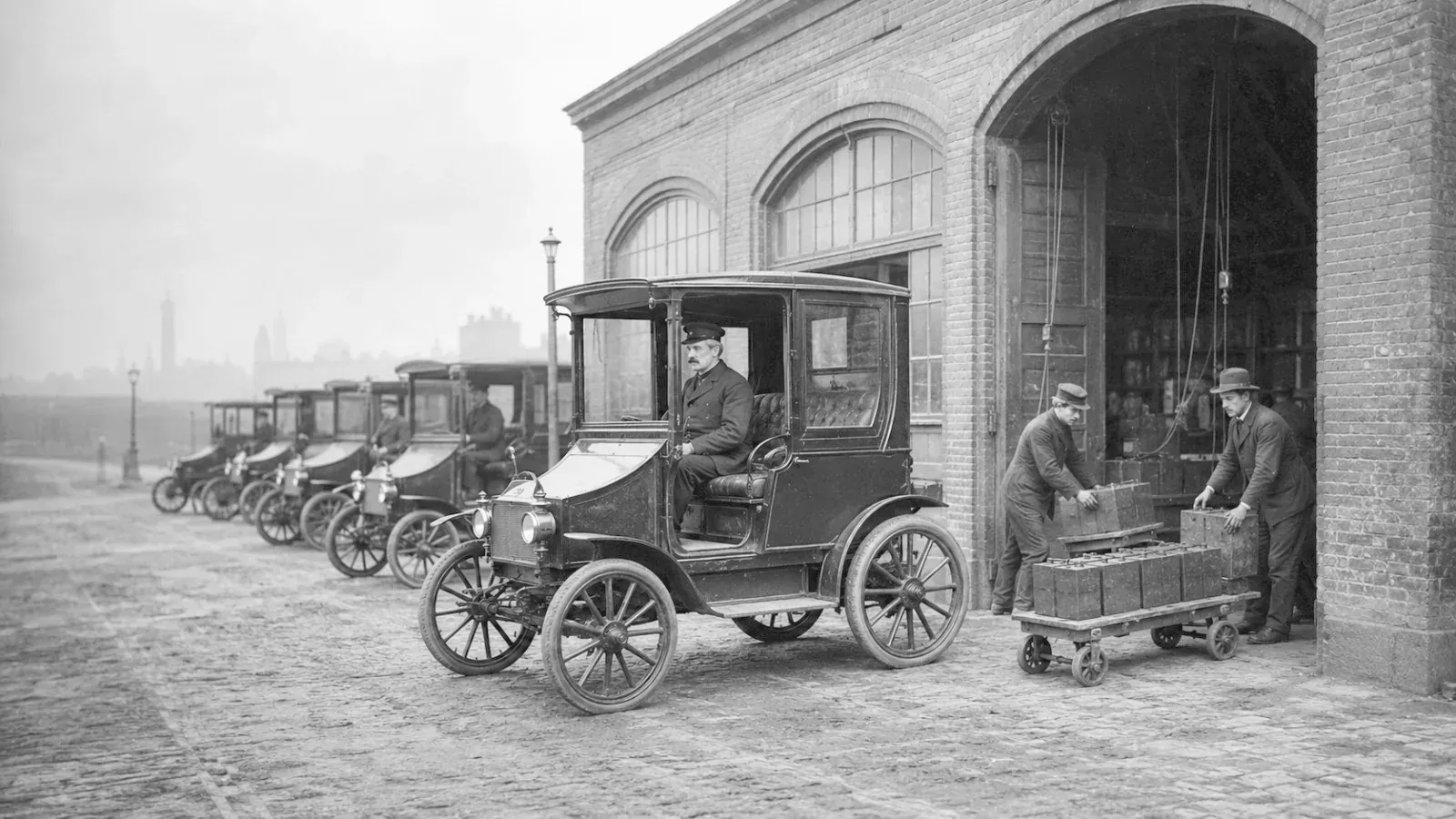 Electric taxi depot, crews carrying battery crates on a trolley.