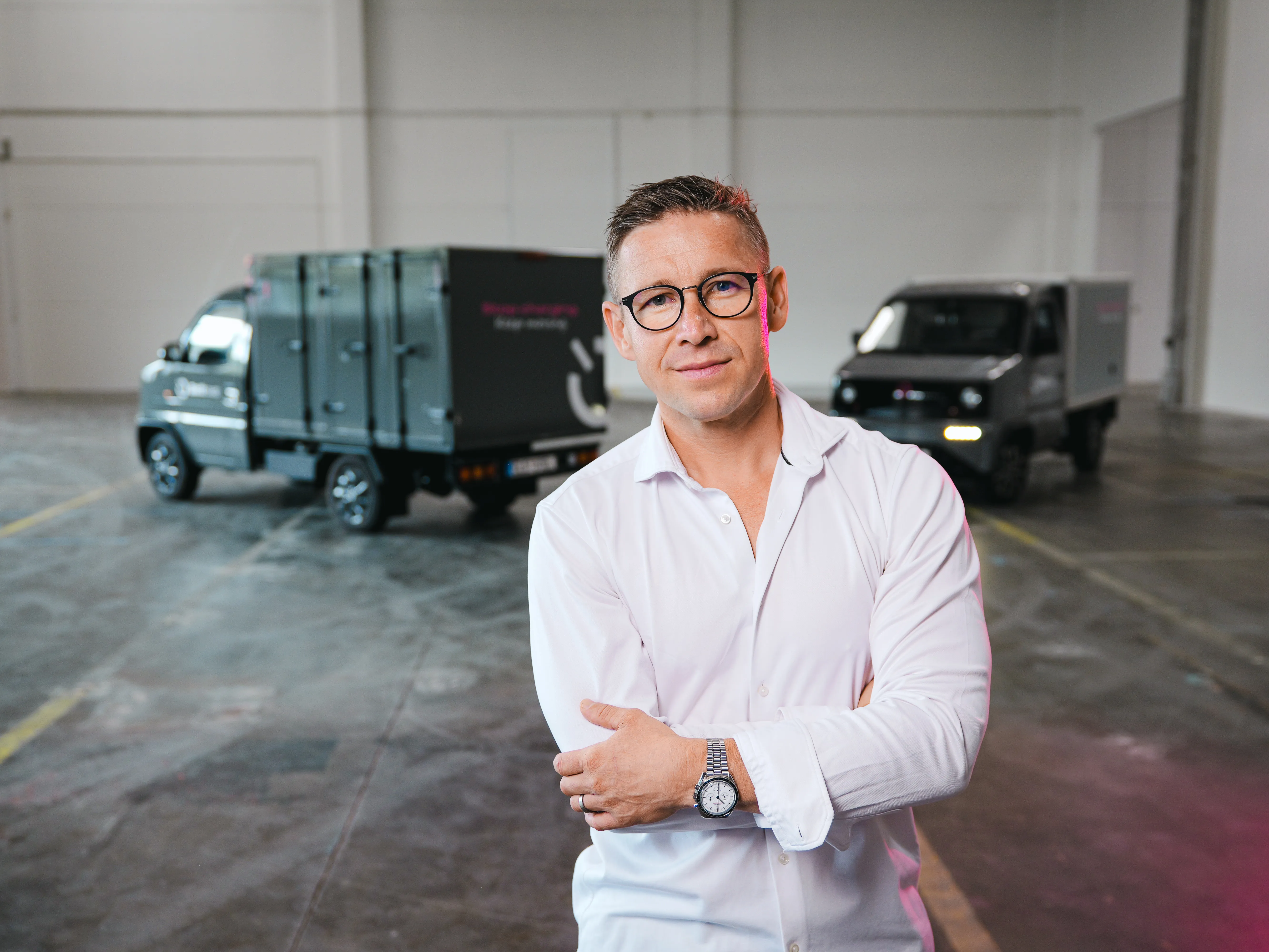 Radek Janků, Battswap's founder and CEO, in a hall with two Battswap vans behind him.